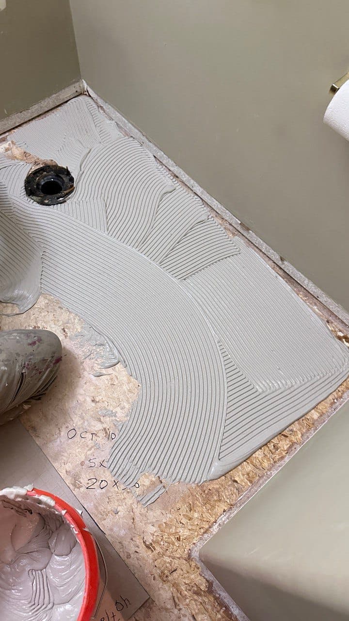 Application of thin-set mortar on a subfloor with precise trowel lines for tile installation